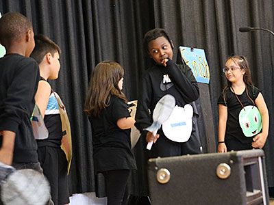 Five drama club students perform a skit on stage 