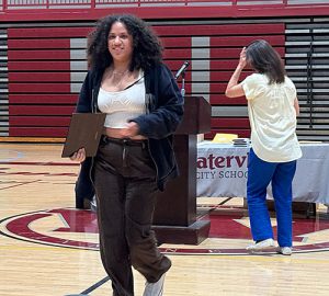A student accepts an award and smiles at the camera during the annual Sports Awards ceremony