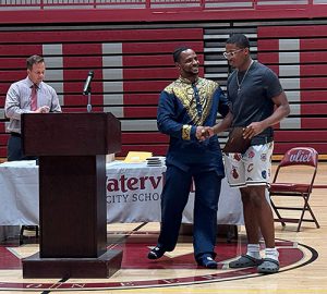 A student accepts an award and shakes hands with coach during the annual Sports Awards ceremony