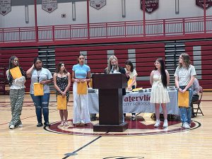 Members of cheer team receive awards from coach 