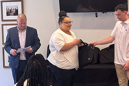Student is presented with a laptop bag as WHA executive director stands nearby