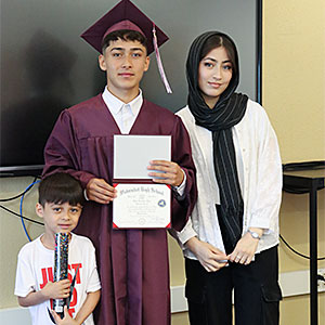 Graduate stands with family members while holding diploma