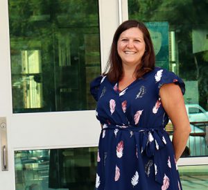 Student Support Services Coordinator is a blue dress stands in front of the main entrance to the school.