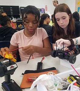 Two students work together to prepare a radio-controlled car for a race