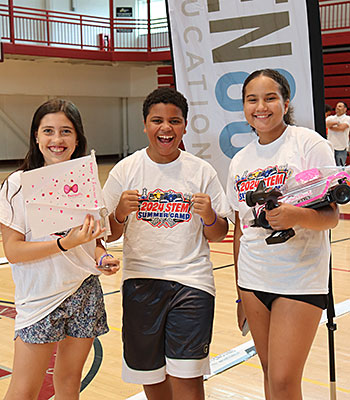 The Powerpuff team stands together smiling and celebrating victory with their radio-controlled car