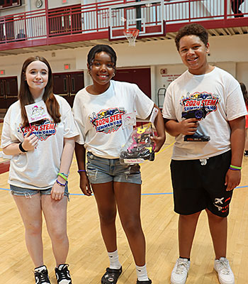 Members of the Dream Team stand together while holding their radio-controlled car and its controller