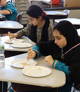 Two students compete in a Cheerio challenge involving toothpicks during minute to win it Olympics 