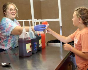 A student accepts a snow cone from a staff volunteer