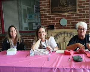 Three staff volunteers get ready to greet students and families