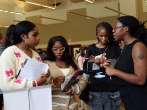 Three student speak with a college admission representative