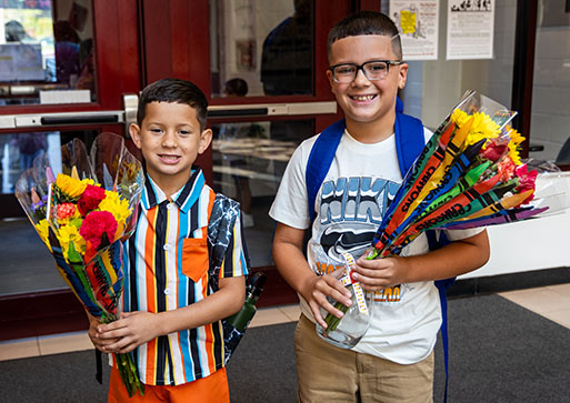 Two elementary students carry flowers