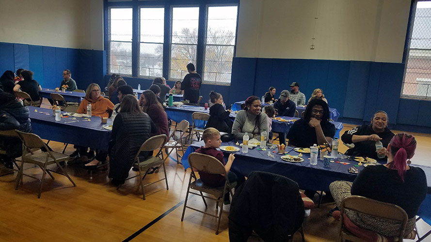 Families and students gathered round tables with plates of food