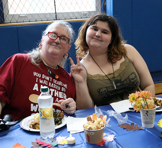 A student and adult family member are seated together at a table eating lunch