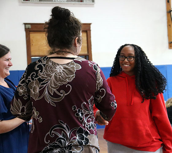 A smiling student receives an award certificate from an administrator