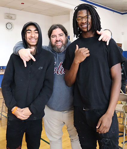 The assistant principal stands between two students who are smiling