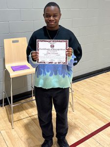 A student holds Kids of Character certificate