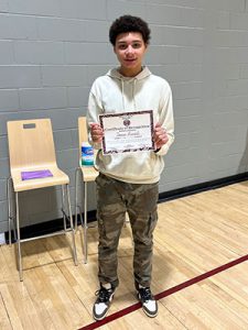 A student holds Kids of Character certificate