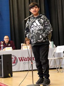 A student stands at the microphone ready to compete in spelling bee