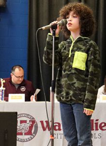 A student stands at the microphone ready to compete in spelling bee