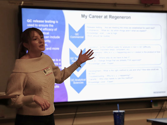 A scientist stands in front of class speaking to students about careers